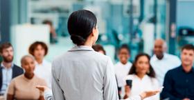 Foto que muestra a una persona de espaldas exponiendo frente a un grupo de personas